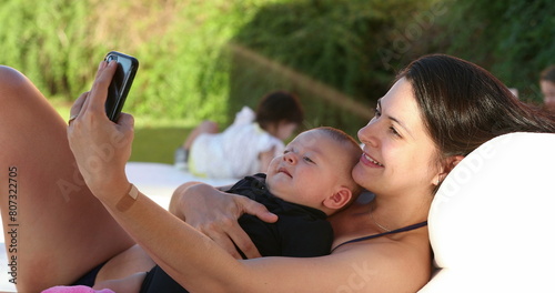 Mom and baby taking selfie together outside by the pool © Marco
