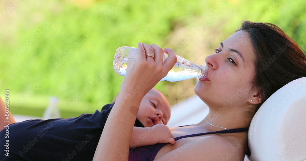 Mother drinking bottle of water while holding sleeping baby Mother drinking bottle of water while holding sleeping baby
