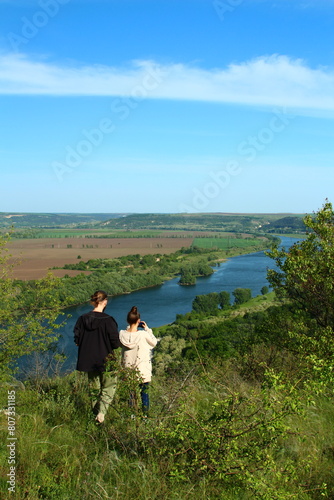 A group of people standing on a hill overlooking a river