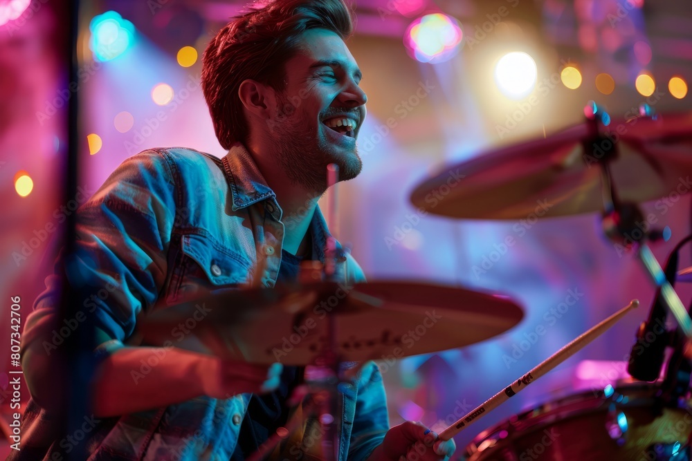 A cheerful male drummer playing energetically on stage, with his hands a blur as they strike the drums