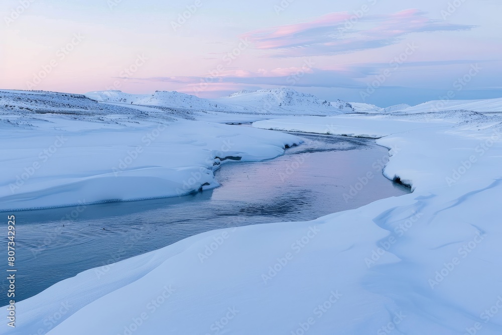 A panoramic view of a winding river cutting through a snow covered landscape at dusk