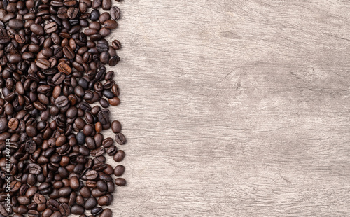 Closeup of coffee beans over rustic wooden table with copy space