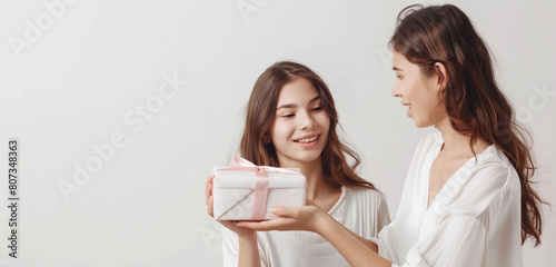 Mother's Day surprise--daughter presents lovingly wrapped gift to her mother against a serene white background.