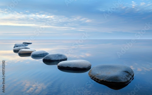 Smooth stones lined up on a serene water surface under a soft blue sky.