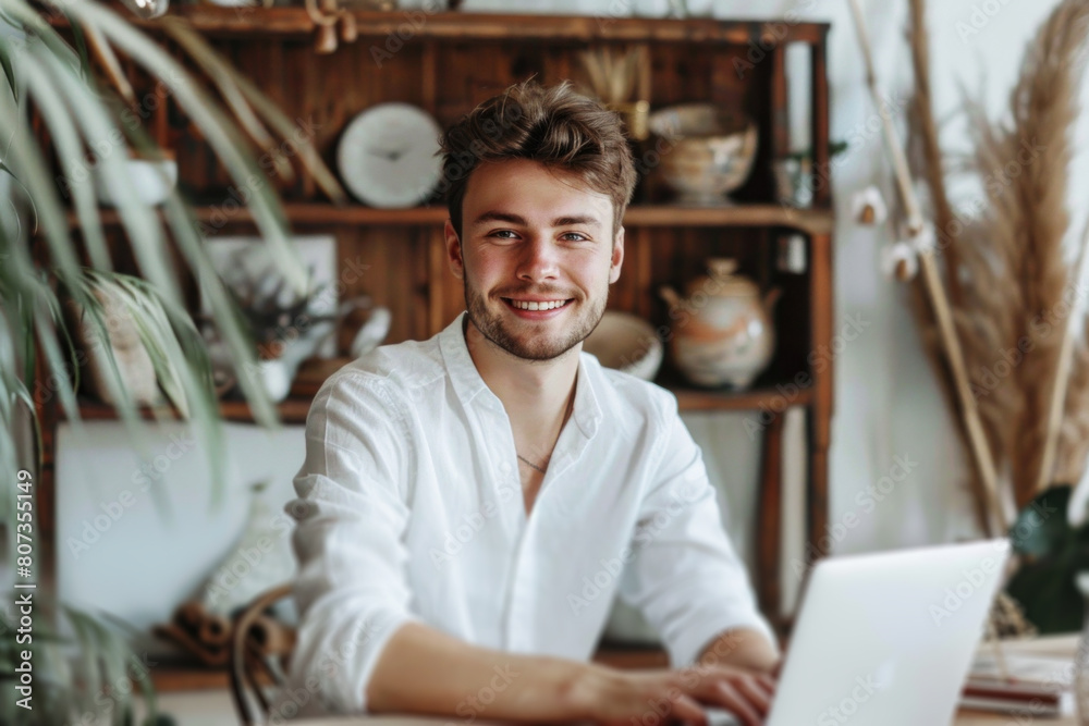 Obraz premium Portrait of a handsome smiling young man using laptop