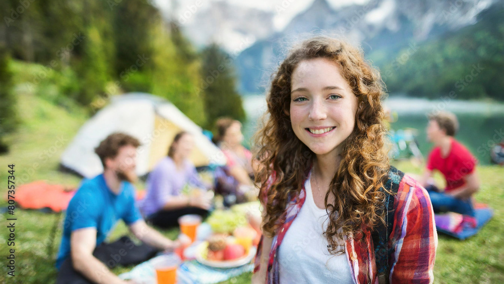 Portrait of smiling young woman with friends on background at campsite
