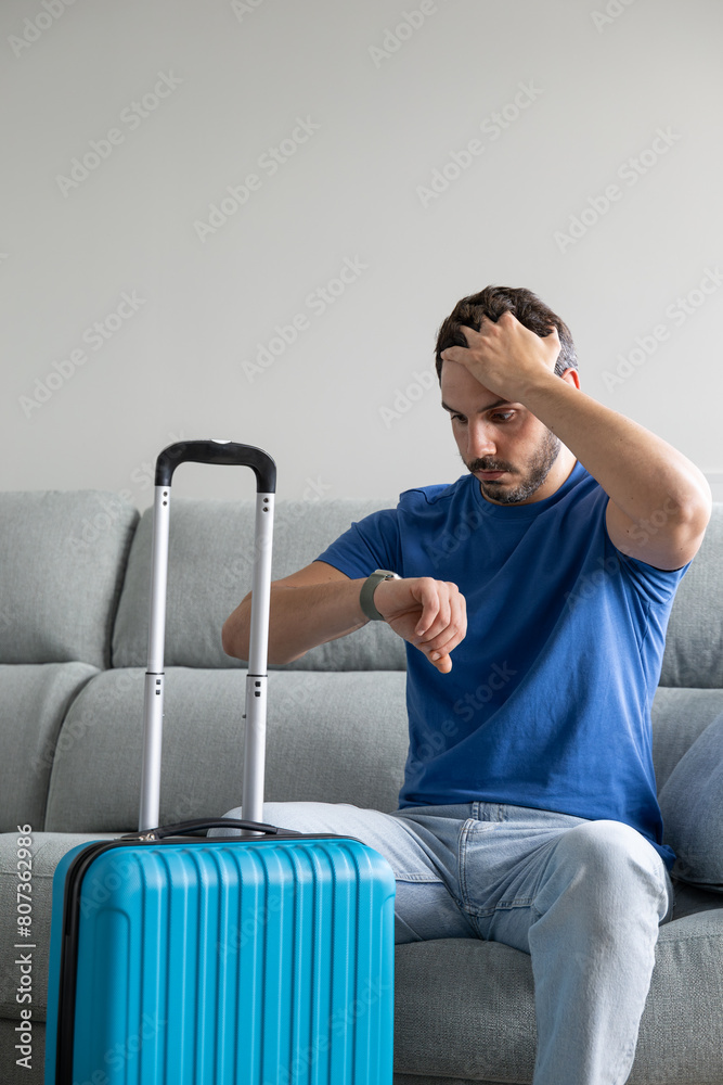 Man checking the time before catching a flight with suitcases prepared at home Man checking the time before catching a flight with suitcases prepared at home