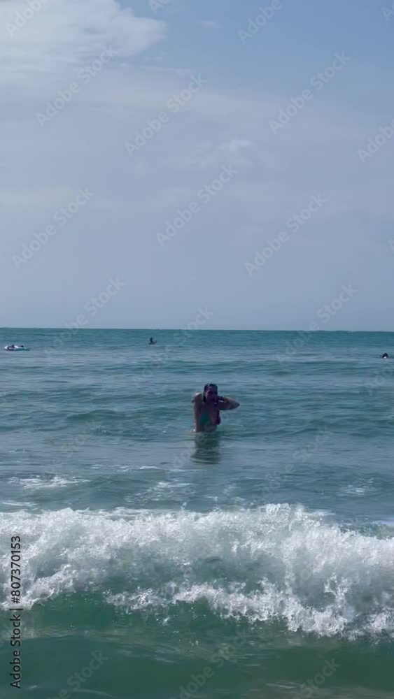 Woman Walking in Ocean Waves on Sunny Day Woman Walking in Ocean Waves on Sunny Day