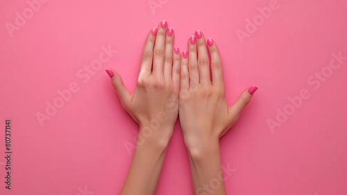 Young woman's hands on a pastel pink background with copyspace. Body care tender concept.
