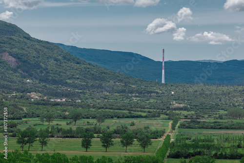 Smokestack or chimney of coal powerplant in Plomin, Croatia in the istrian region. Chimney surrounded by lush greens photo