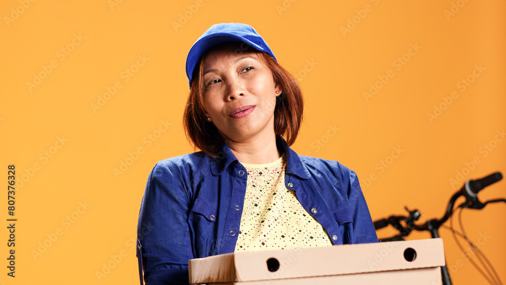 Hasty BIPOC employee waiting for client to answer door and pick up meal order. Portrait of bored courier isolated over studio background carrying stack of pizza boxes, close up Hasty BIPOC employee waiting for client to answer door and pick up meal order. Portrait of bored courier isolated over studio background carrying stack of pizza boxes, close up