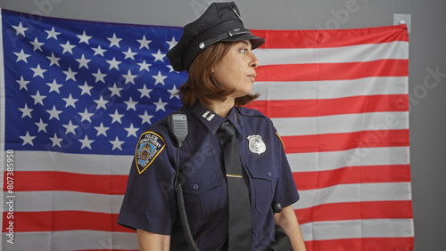 Mature hispanic policewoman in uniform stands before an american flag, symbolizing law enforcement in the usa.