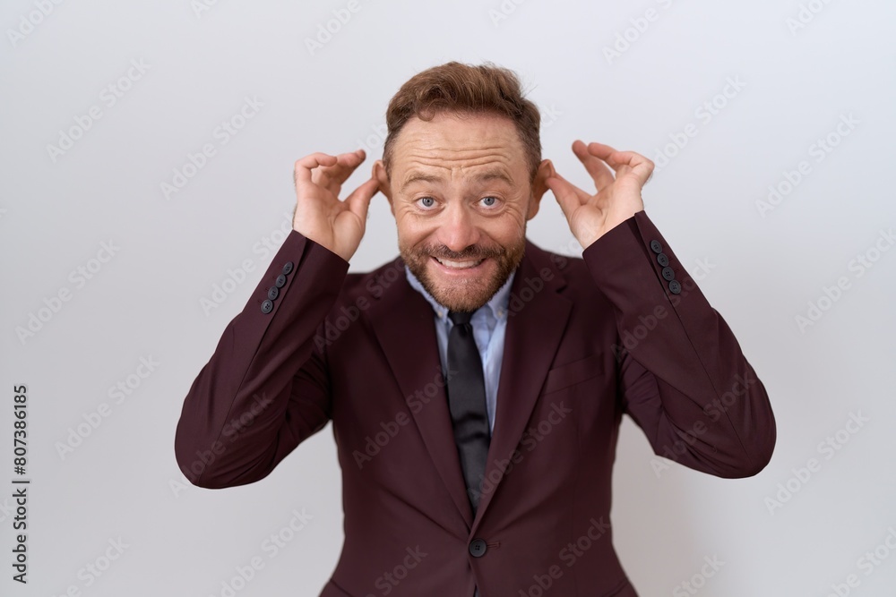 Middle age business man with beard wearing suit and tie smiling pulling ears with fingers, funny gesture. audition problem Middle age business man with beard wearing suit and tie smiling pulling ears with fingers, funny gesture. audition problem