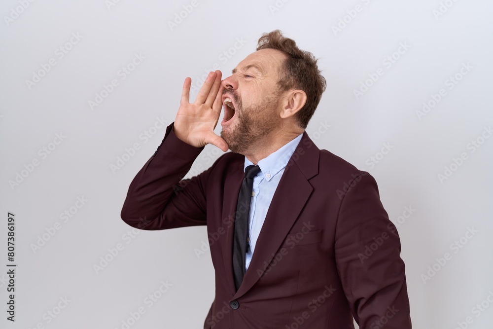 Middle age business man with beard wearing suit and tie shouting and screaming loud to side with hand on mouth. communication concept. Middle age business man with beard wearing suit and tie shouting and screaming loud to side with hand on mouth. communication concept.