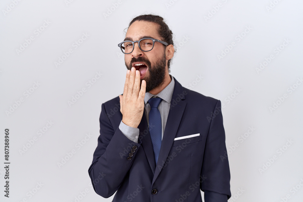 Hispanic man with beard wearing suit and tie bored yawning tired covering mouth with hand. restless and sleepiness. Hispanic man with beard wearing suit and tie bored yawning tired covering mouth with hand. restless and sleepiness.