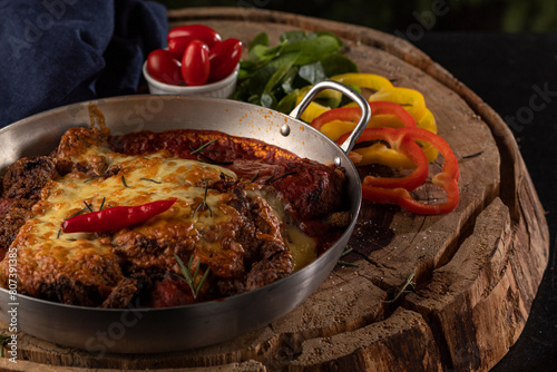 Bife à Parmegiana em panela de alumínio com pimenta decorativa