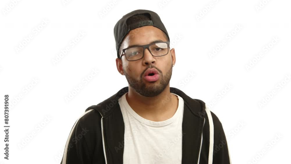 A young multiracial man with glasses and wearing a stylish cap, shakes his head in disapproval, his braces visible as he expresses a clear no on a white background. Camera 8K RAW. A young multiracial man with glasses and wearing a stylish cap, shakes his head in disapproval, his braces visible as he expresses a clear no on a white background. Camera 8K RAW.