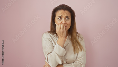 Obraz na plátně An anxious hispanic woman in a beige blouse poses against a solid pink background, appearing contemplative and concerned