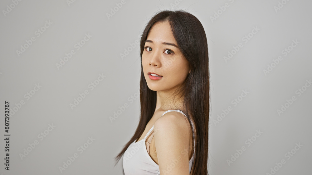 A young chinese woman poses casually against an isolated white background, epitomizing natural beauty. A young chinese woman poses casually against an isolated white background, epitomizing natural beauty.