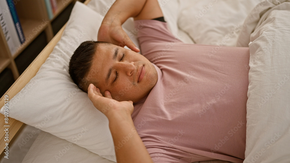 Exhausted young latin man finds serene comfort at home, relaxing as he falls asleep on the cozy bed of his indoor bedroom, resting amidst the background of morning tranquility. Exhausted young latin man finds serene comfort at home, relaxing as he falls asleep on the cozy bed of his indoor bedroom, resting amidst the background of morning tranquility.