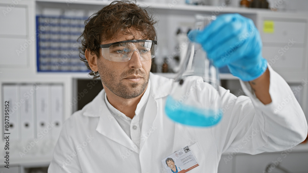 Hispanic scientist examines blue liquid in flask at medical laboratory Hispanic scientist examines blue liquid in flask at medical laboratory