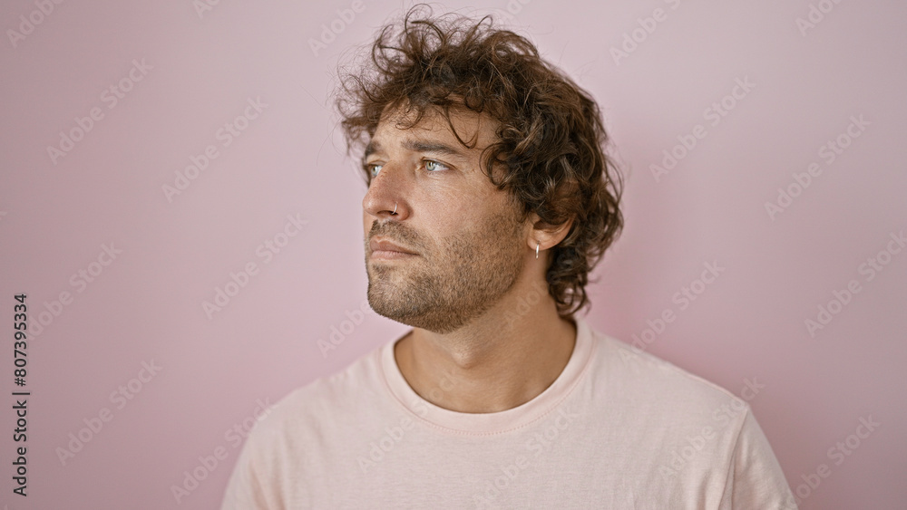 Handsome hispanic man with curly hair posing thoughtfully against a plain pink background Handsome hispanic man with curly hair posing thoughtfully against a plain pink background