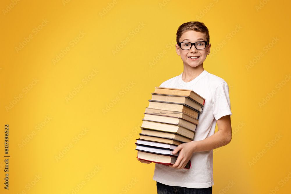 A young boy standing and holding a stack of books in his arms. A young boy standing and holding a stack of books in his arms.