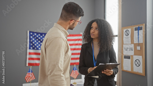 A man and woman converse in a usa electoral center with american flags, suggesting a governmental setting. photo