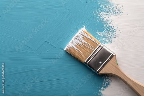 A paintbrush is laying on a blue wall with white paint