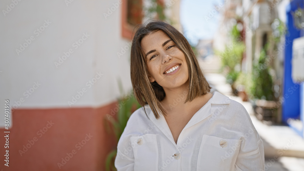 Young beautiful hispanic woman standing smiling at typical spanish old town Young beautiful hispanic woman standing smiling at typical spanish old town