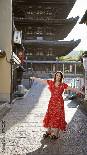 Joyful hispanic woman embracing freedom, arms wide open smiling on gion's kyoto street enjoying the old traditional town's beauty