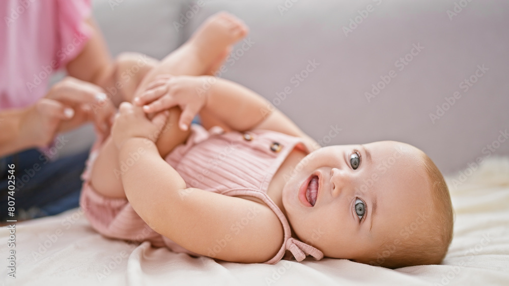 Mother holding baby's legs playing indoor family game at home – lovely woman and daughter play together on living room sofa Mother holding baby's legs playing indoor family game at home – lovely woman and daughter play together on living room sofa