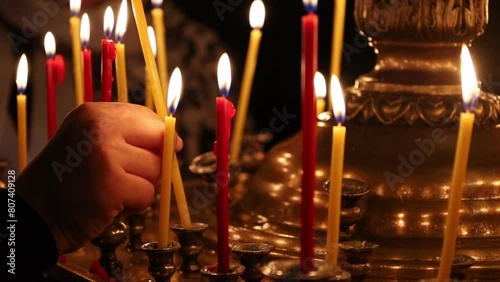 Hand placing a burning candle on a candilia on Easter night