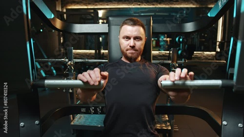 A man is performing a weightlifting gesture in the gym, focusing on his thigh muscles. The barbell machine is aiding in his workout to strengthen his legs