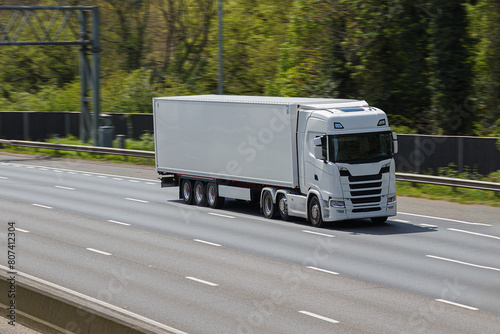 White, single no name lorry travelling on the the motorway in a sunny day with no other cars around.