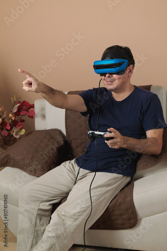 Portrait Latin adult with mixed reality headset playing in living room, virtual reality video game concept, pointing with the finger