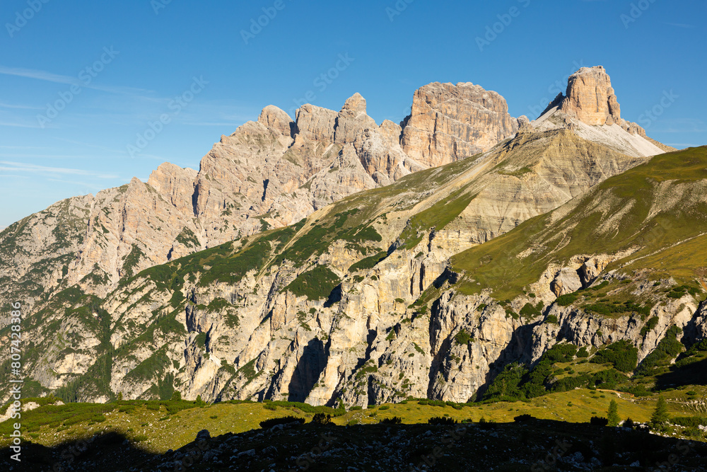 Scenic summer mountain landscape of Italian Dolomites range with views of Torre dei Scarperi rocky peaks and slopes covered with green meadows and forests