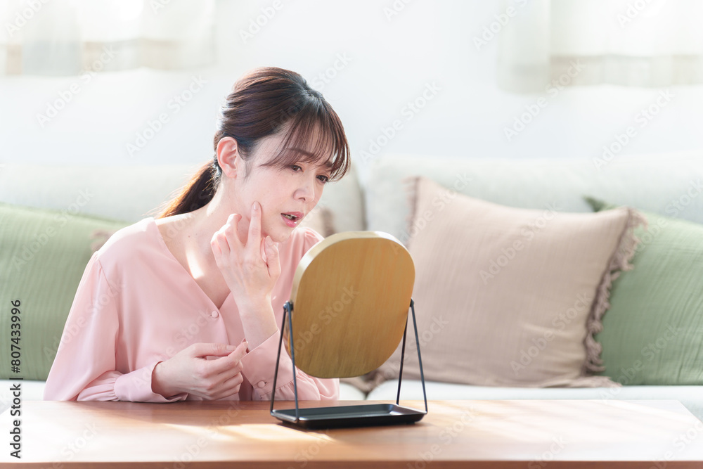 リビングで鏡を見る女性　肌荒れ　トラブルイメージ