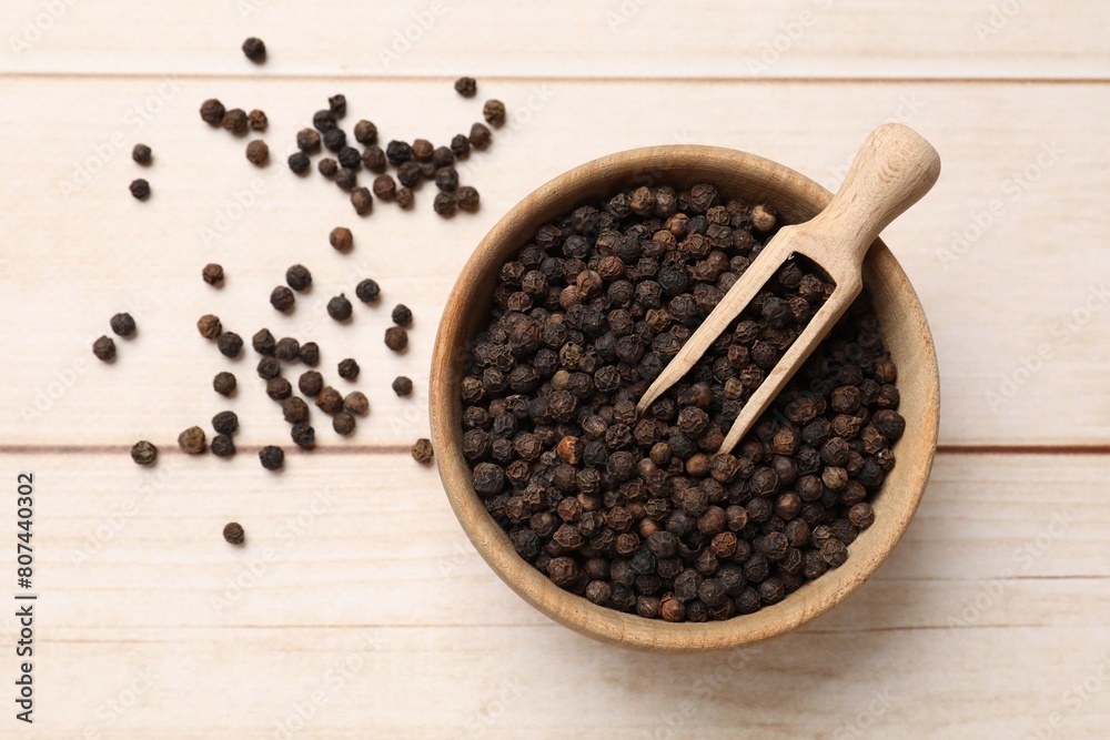Aromatic spice. Black peppercorns and scoop in bowl on wooden table, top view Aromatic spice. Black peppercorns and scoop in bowl on wooden table, top view