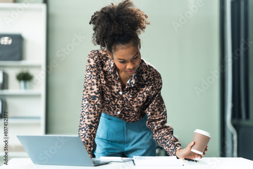 A young African American woman in a blue formal shirt with afro brown hair works as a product designer in a modern office, utilizing skills in design, CAD, CNC, and CNF.