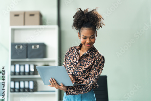 A young African American woman in a blue formal shirt with afro brown hair works as a product designer in a modern office, utilizing skills in design, CAD, CNC, and CNF. photo