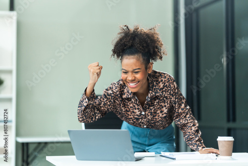 A young African American woman in a blue formal shirt with afro brown hair works as a product designer in a modern office, utilizing skills in design, CAD, CNC, and CNF. photo