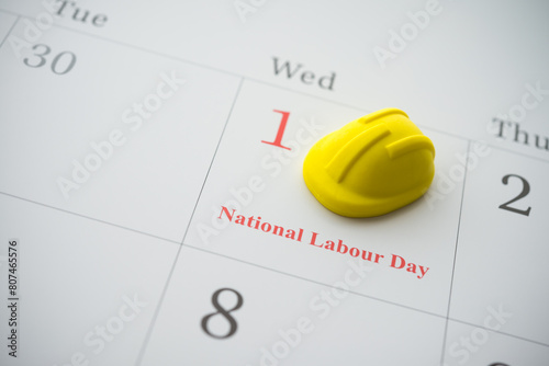 Yellow safety helmet on 1 st May white calendar background with copy space. National labour day or international workers day concept. Labor rights, safety and health on workplace.