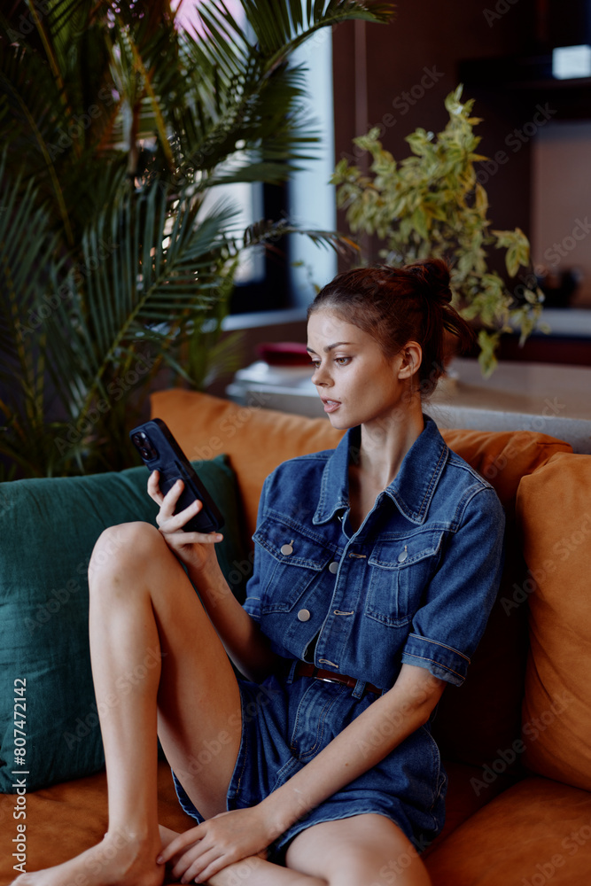 Obraz premium Young woman sitting on a couch, absorbed in her cell phone, engrossed in digital world