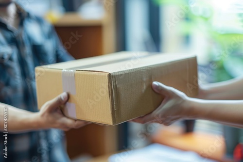 Close up of hands handing over cardboard box to delivery man.