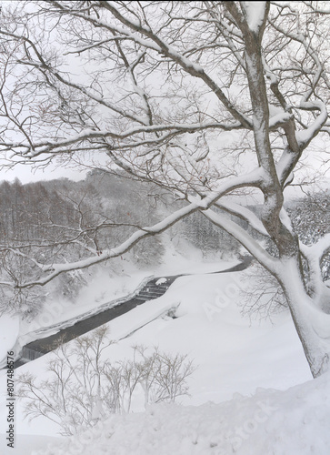 Beautiful Japanese satoyama winter scenery with forest oh the hill covered with snow, mountain river with dam in Ginzan onsen photo