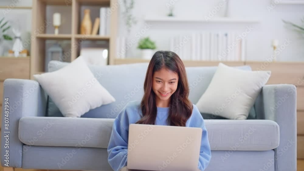 Young asian woman smile working in living room at home. Happy female using computer laptop and sitting on the floor beside couch at house, Video call with friend Young asian woman smile working in living room at home. Happy female using computer laptop and sitting on the floor beside couch at house, Video call with friend