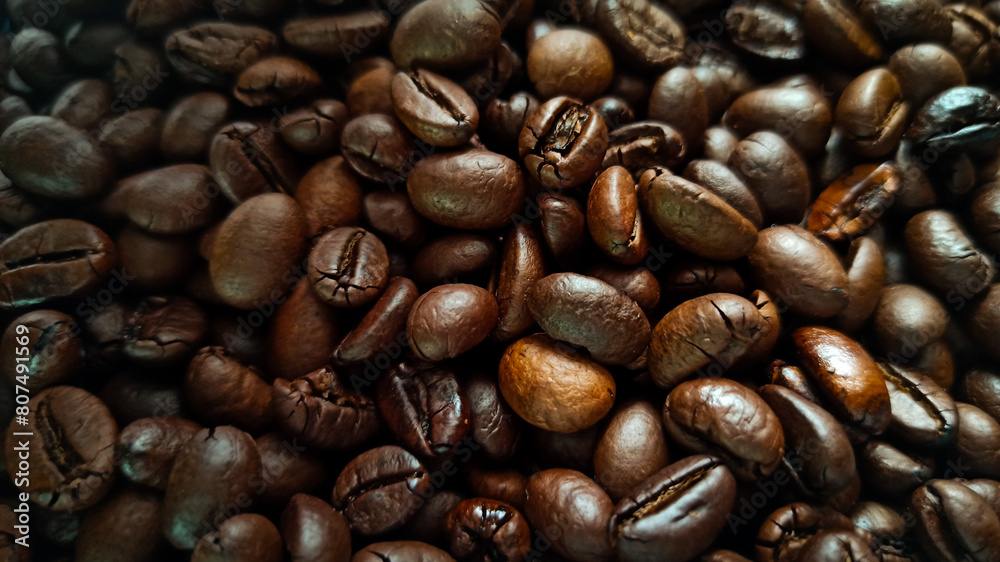 There is a close up of freshly roasted coffee beans on a blue placemat