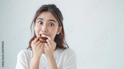 A woman is eating a donut with a surprised expression on her face