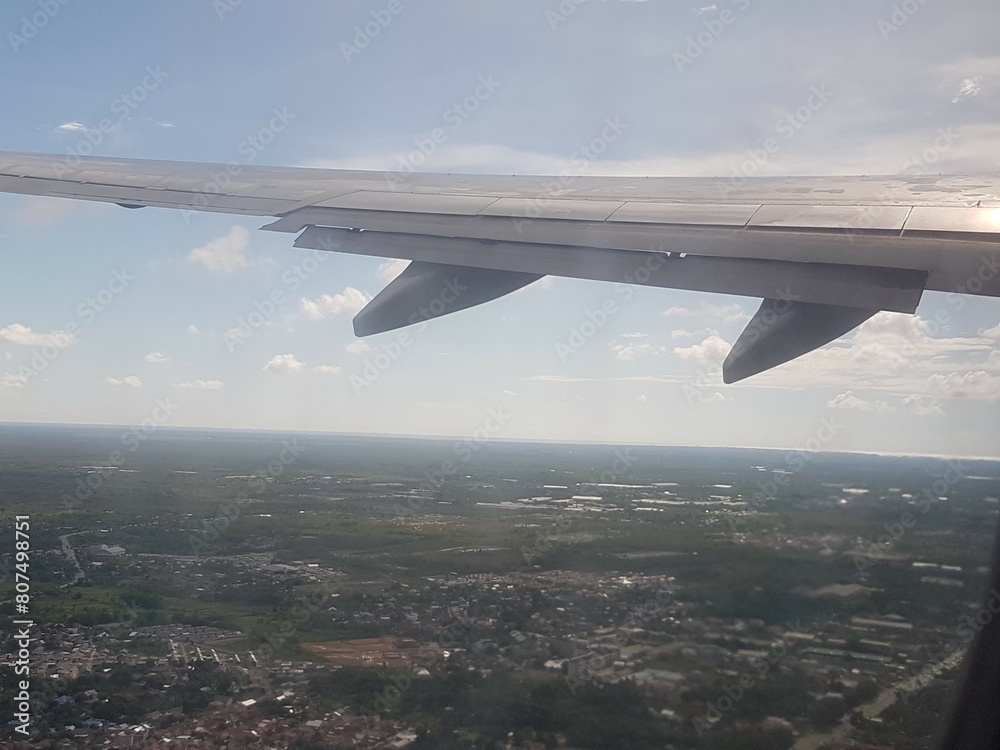 Looking through window aircraft during flight in wing with a nice blue clear sky and beautiful clouds. flying and traveling, view from airplane that can see outside.